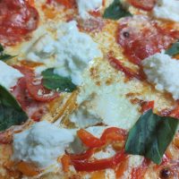 La Pizza Nîmoise est une création audacieuse inspirée des saveurs méridionales, mettant en avant des ingrédients typiques de la région. Sur une base de crème onctueuse et de mozzarella, cette pizza est garnie de brandade de morue délicate, de tranches de chorizo épicé, de tomates cerises juteuses, de poivrons grillés et de basilic frais. Elle est finalisée à la sortie du four avec du fior di latte crémeux, apportant une touche fondante et parfumée.

Chez Sancta Maria 1187, nous préparons cette pizza avec soin, en la cuisant sur pierre de lave pour obtenir une pâte à la fois légère et croustillante, qui rehausse parfaitement chaque ingrédient. Dans notre restaurant, situé dans l’ancien réfectoire voûté de la chapelle Notre Dame des Eaux à Balaruc-les-Bains, la Pizza Nîmoise offre une expérience gustative unique et généreuse, inspirée des saveurs de la Méditerranée.

Lors des soirées d'été, dégustez-la dans notre jardin fleuri, en plein centre de Balaruc-les-Bains, à deux minutes du bord de l’étang, pour une expérience en plein air qui célèbre les saveurs méditerranéennes dans une ambiance conviviale et authentique.